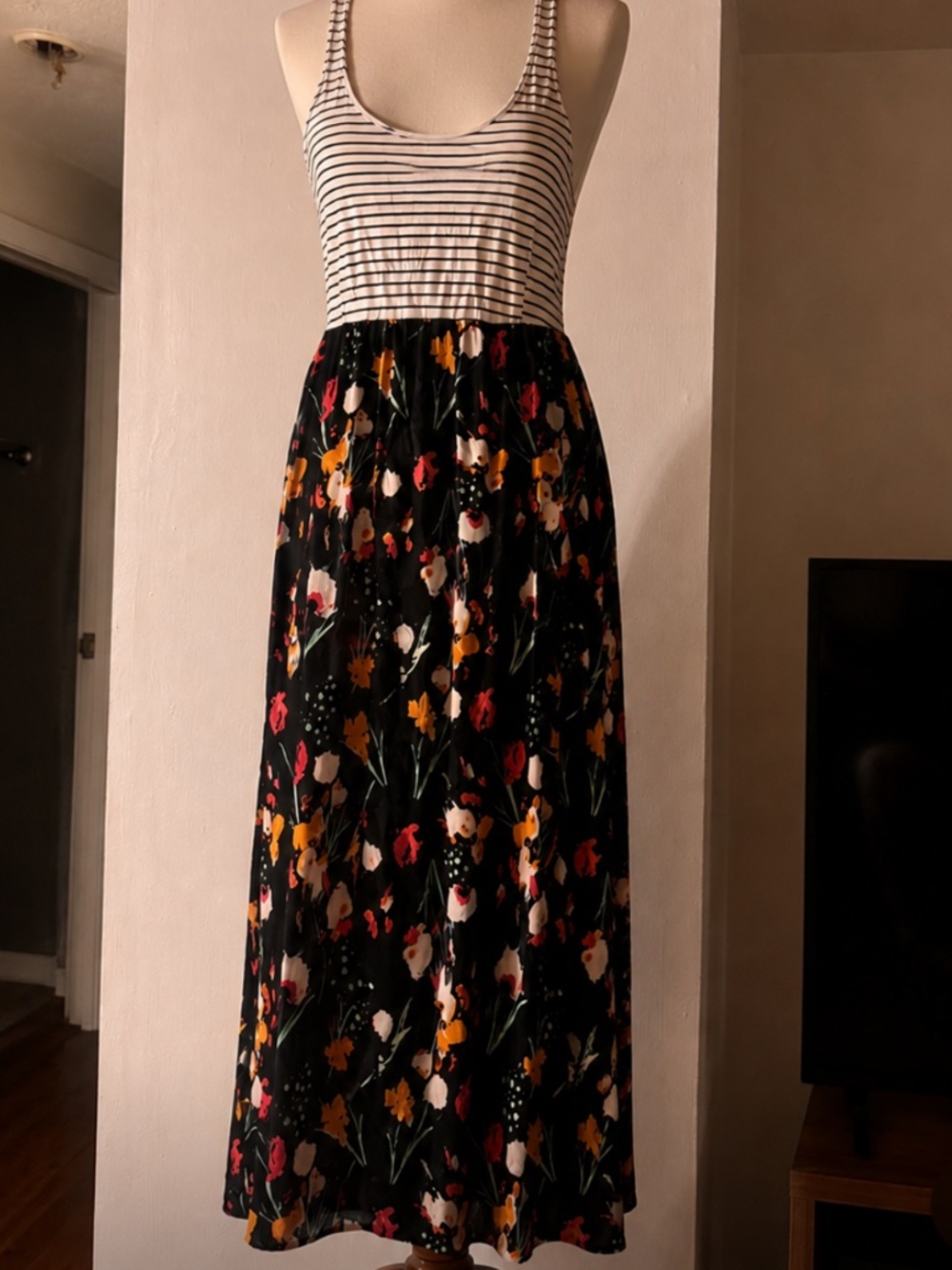 Sleeveless maxi dress with a striped tank-style top. Black skirt features a mult